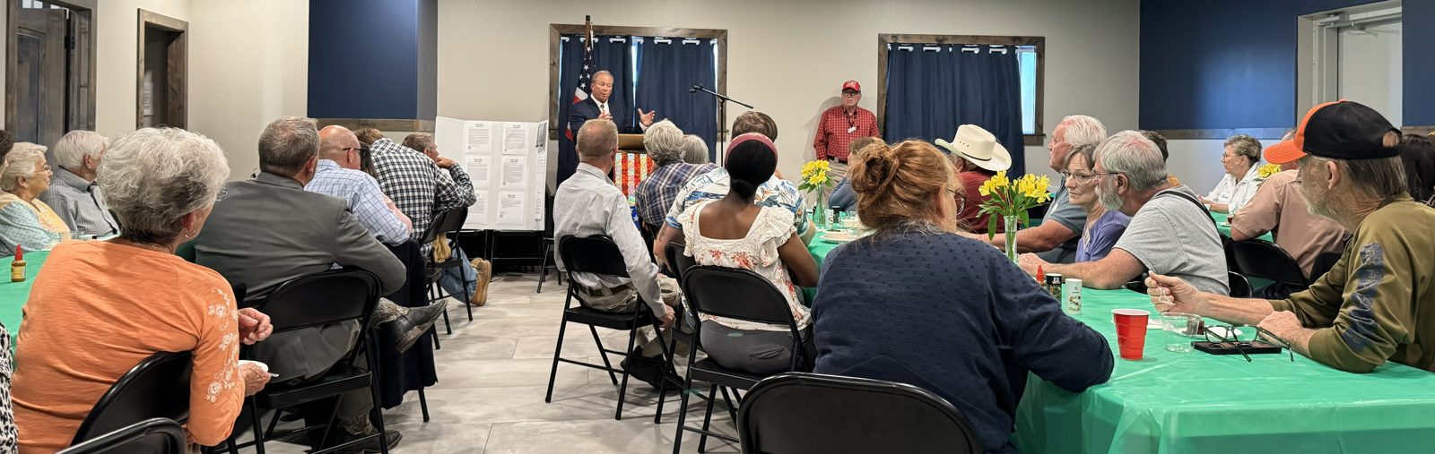 Brent Bien speaking to a packed room of Wyoming voters in front of the American flag